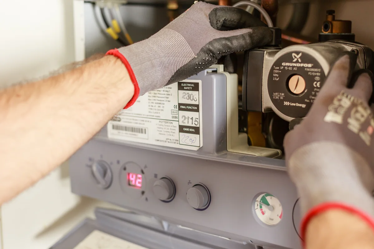 Technician adjusting a heating system control and gauge